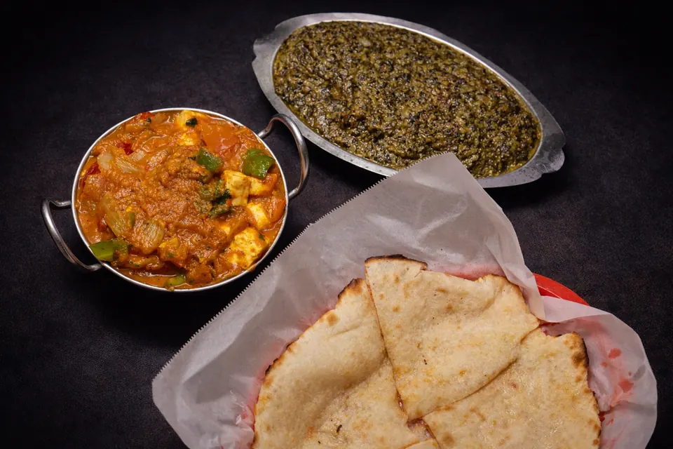 A spread of India Palace dishes: paneer curry, saag and fresh naan